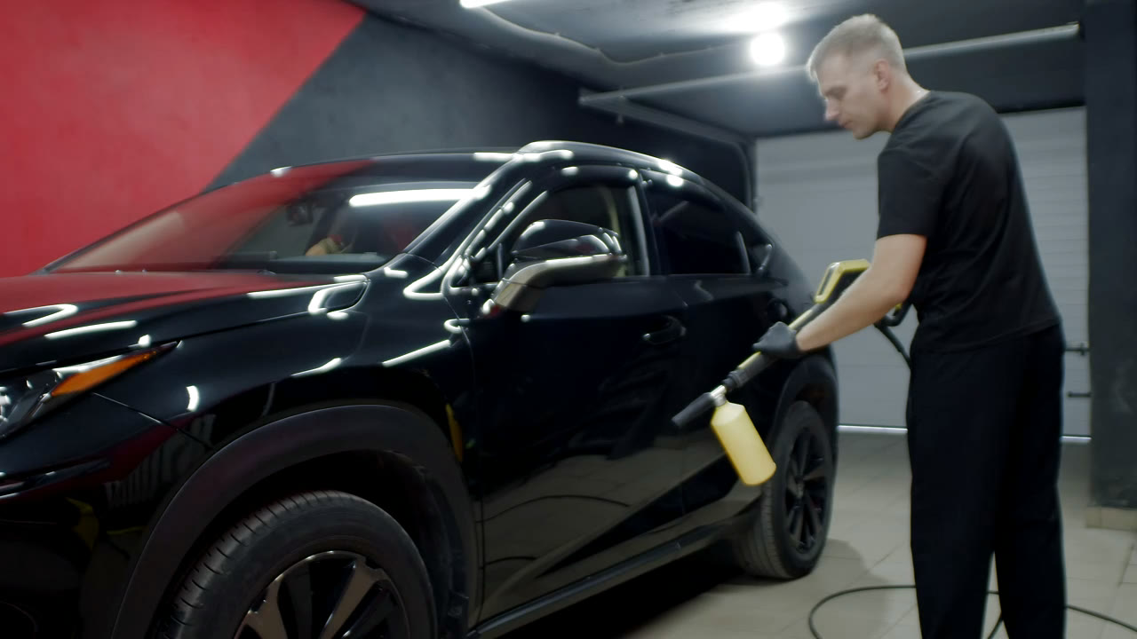 Glossy black sports car being detailed
